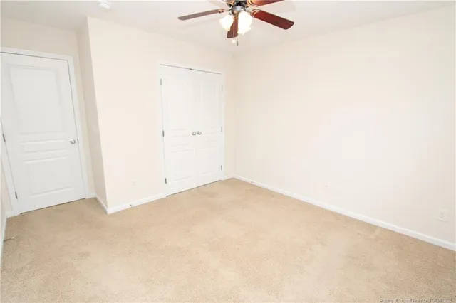 an empty room with a ceiling fan and carpet