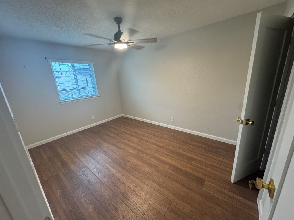 2401 Manor Road, Unit 118 Austin, TX 78722 - Photo 7 of 8 an empty room with wooden floor and fan