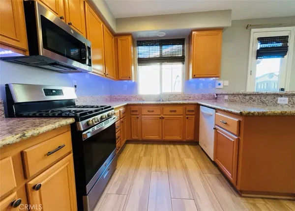 a kitchen with stainless steel appliances granite countertop wooden cabinets a stove top oven a sink and dishwasher
