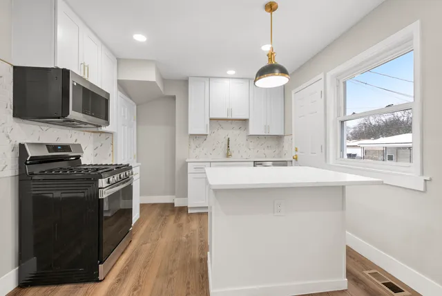 a kitchen with stainless steel appliances granite countertop a stove a sink and a microwave