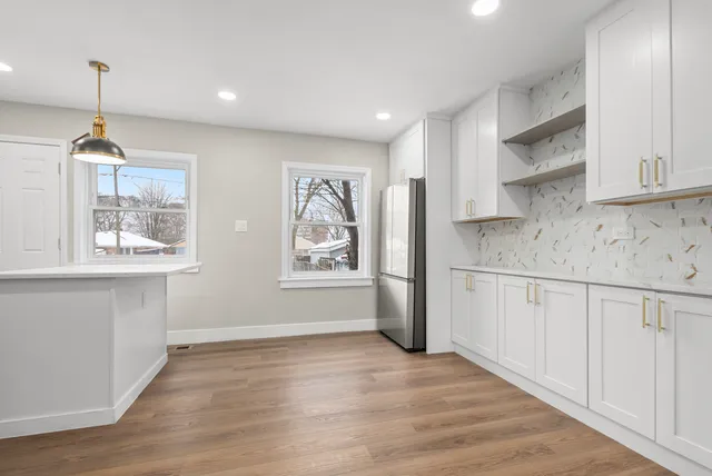 a kitchen with stainless steel appliances granite countertop a refrigerator a sink dishwasher a stove and white countertops with wooden floor