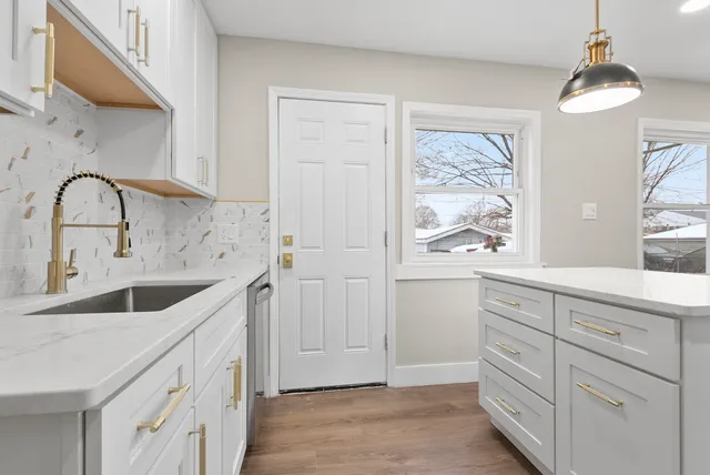 a kitchen with white cabinets and sink