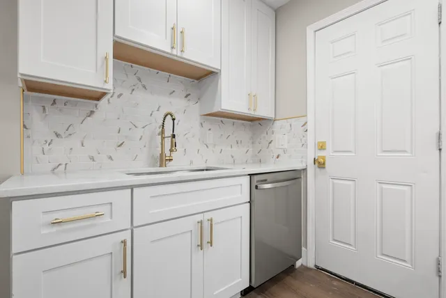 a kitchen with white cabinets and sink