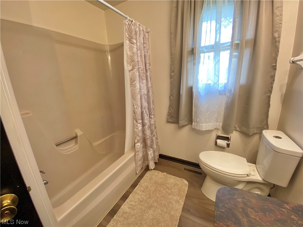 23551 Sandy Creek Road Minerva, OH 44657 - Photo 14 of 35 Bathroom with toilet, hardwood / wood-style flooring, and shower / bath combo