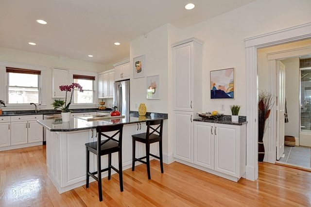 a kitchen with granite countertop white cabinets white stainless steel appliances a sink and a window