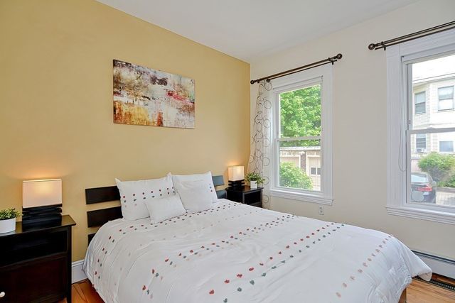 a bedroom with a bed and a large window with wooden floor