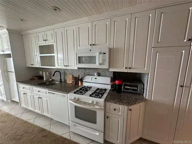 a kitchen with granite countertop white refrigerator and sink