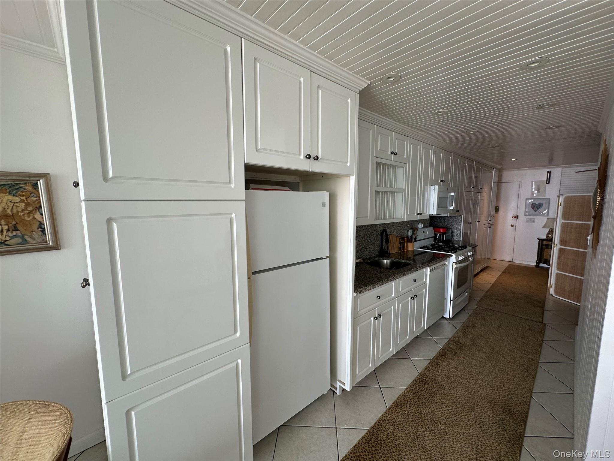 830 Shore Road, Unit 5T Long Beach, NY 11561 - Photo 4 of 18 a kitchen with granite countertop white refrigerator and sink
