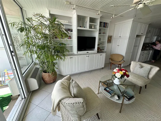 a living room with furniture a flat screen tv and a floor to ceiling window