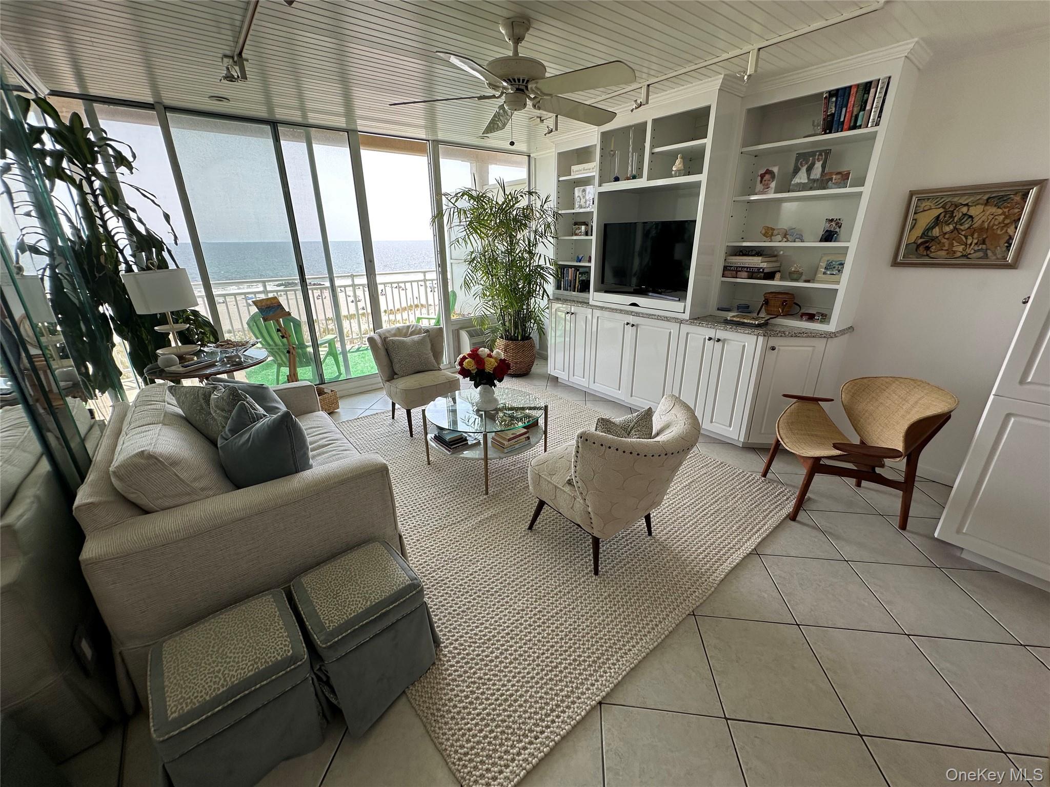 830 Shore Road, Unit 5T Long Beach, NY 11561 - Photo 6 of 18 a living room with furniture a flat screen tv and a floor to ceiling window