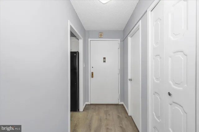 a view of a hallway with wooden floor and a bathroom