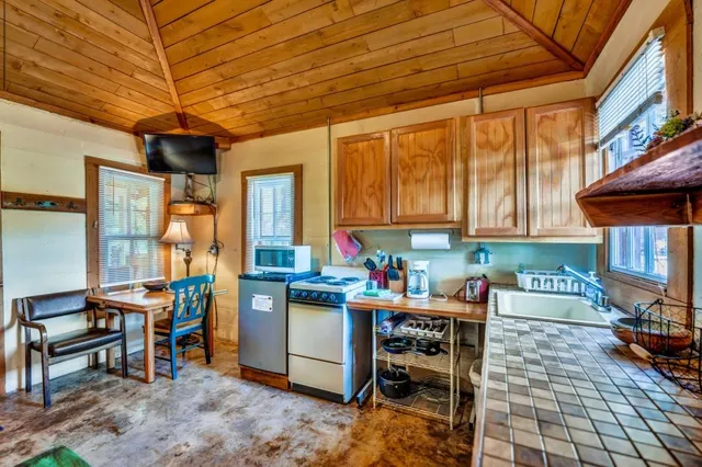 a open kitchen with stainless steel appliances granite countertop a stove a refrigerator a dining table and chairs with the cabinets