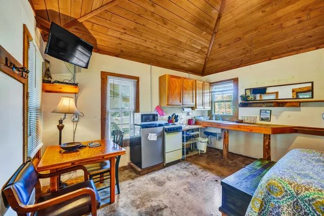 a room with furniture a flat screen tv and kitchen view