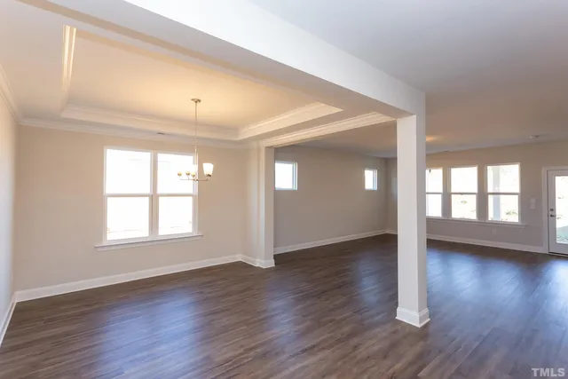 a view of an empty room with wooden floor and window