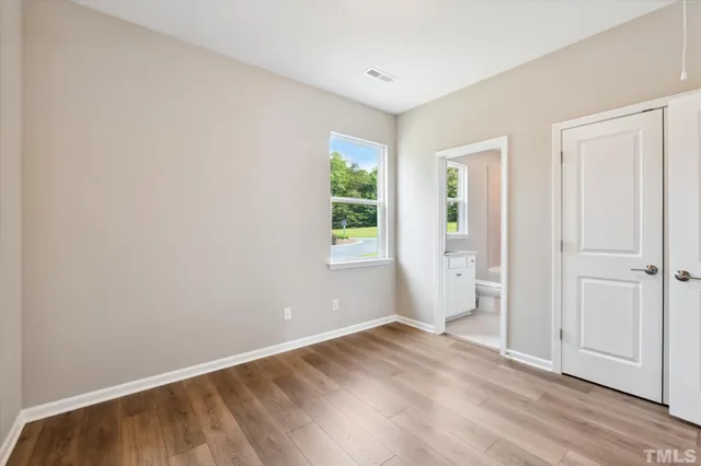 an empty room with wooden floor chandelier and windows