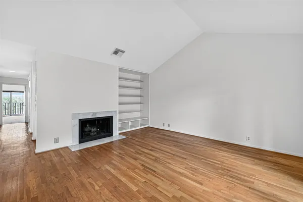 a view of empty room with a fireplace and wooden floor