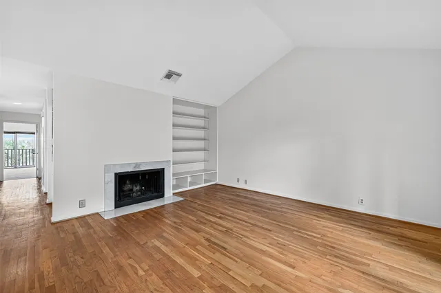 a view of empty room with a fireplace and wooden floor