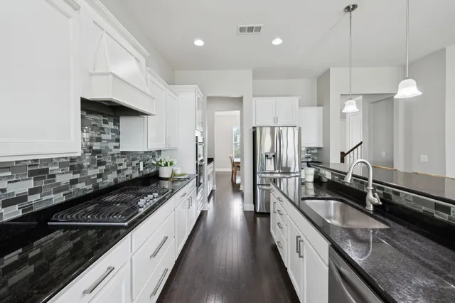 a kitchen with granite countertop a refrigerator sink and stove