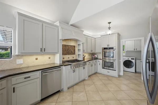 a large white kitchen with a large window appliances and cabinets