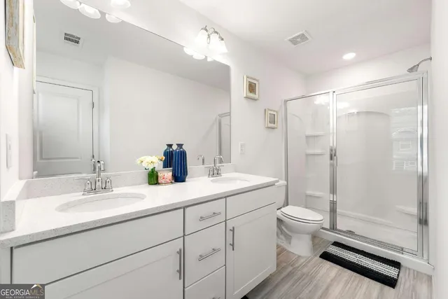 a bathroom with a double vanity sink toilet mirror and shower