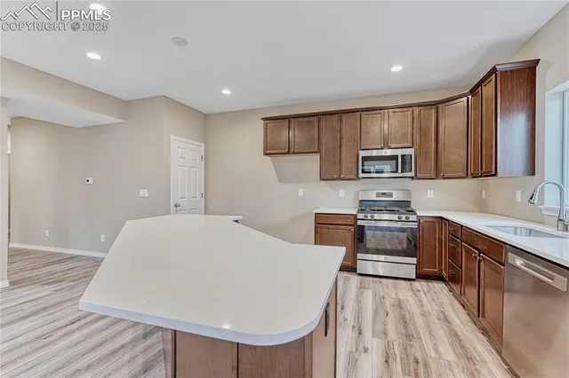 a kitchen with stainless steel appliances a stove top oven a sink dishwasher and a refrigerator with wooden floor