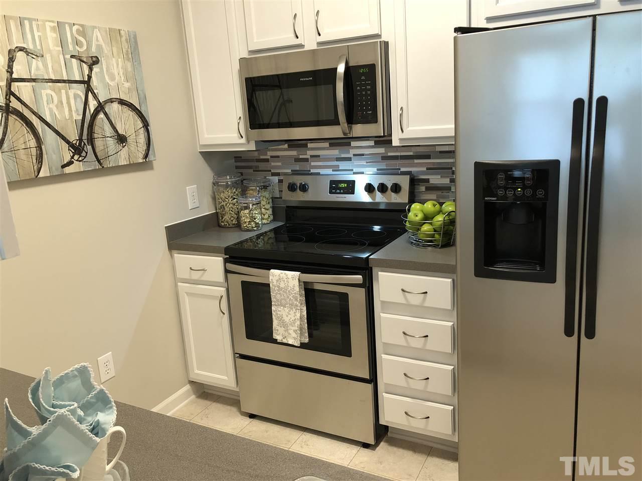 212 West Savannah Ridge Road, Unit 212 Holly Springs, NC 27540 - Photo 6 of 21 a kitchen with stainless steel appliances a stove and a microwave