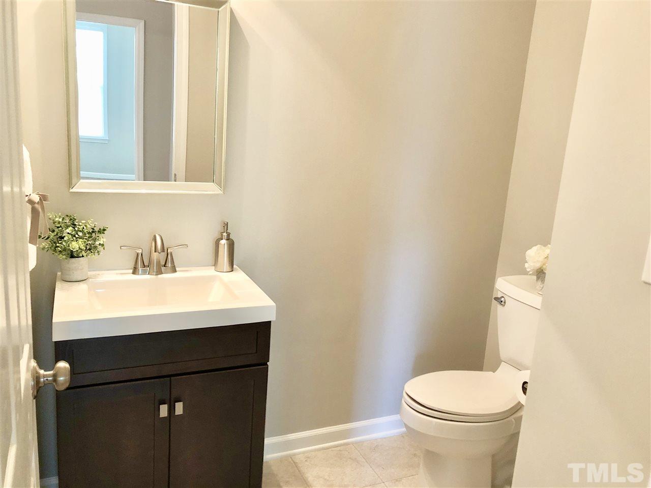 212 West Savannah Ridge Road, Unit 212 Holly Springs, NC 27540 - Photo 10 of 21 a bathroom with a sink a toilet and mirror