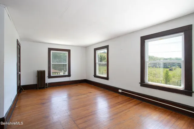 an empty room with wooden floor and windows