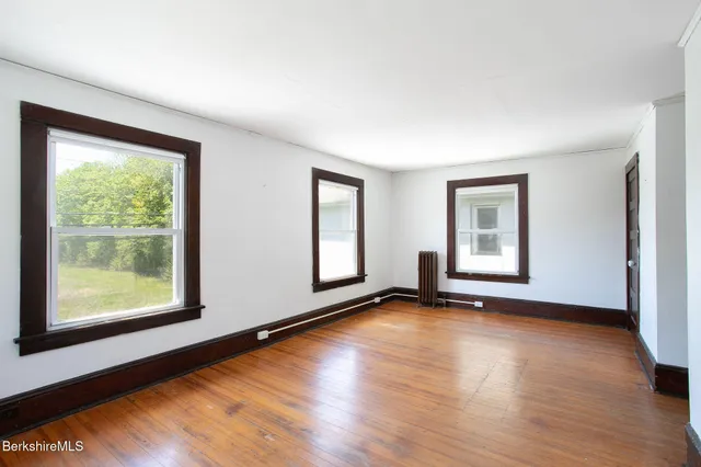a view of an empty room with wooden floor and a window
