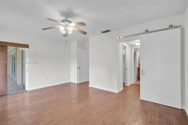a view of a room with wooden floor and a ceiling fan