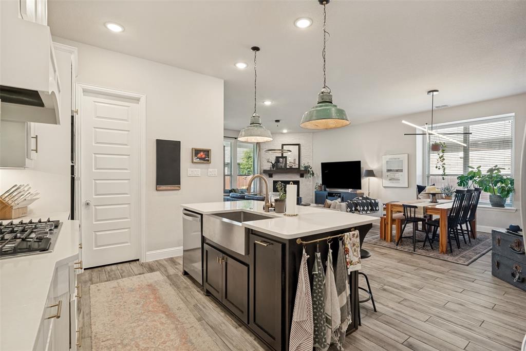 14948 Gentry Drive Aledo, TX 76008 - Photo 13 of 25 Kitchen island with a farmhouse sink and pendant lighting, featuring a gas range and wood-finish flooring