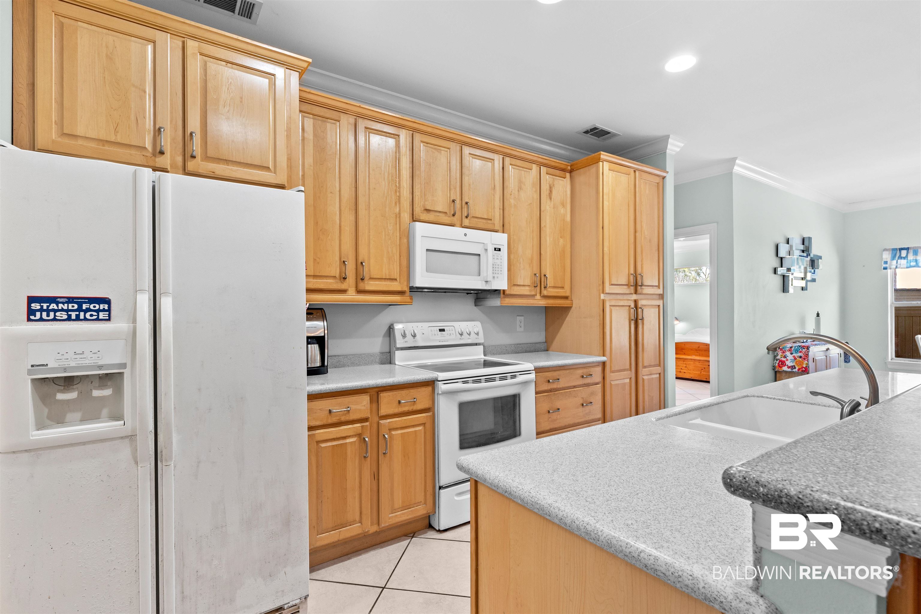 237 Hemingway Loop Foley, AL 36535 - Photo 11 of 49 Kitchen featuring visible vents, ornamental molding, light tile patterned flooring, white appliances, and a sink