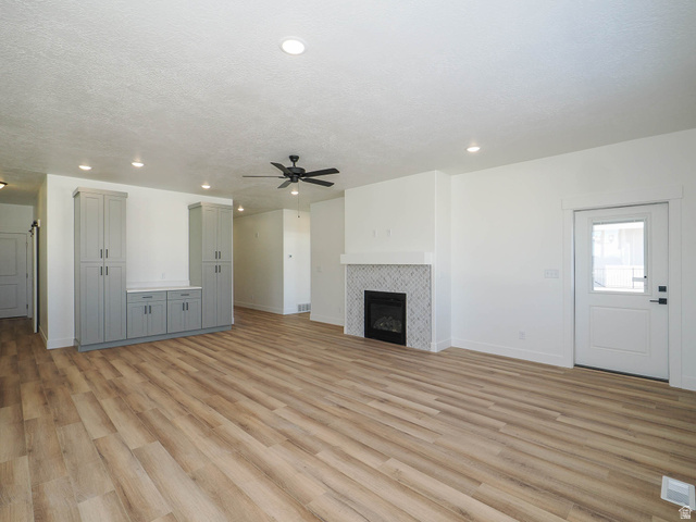 3938 North Wood Road Eagle Mountain, UT 84005 - Photo 11 of 55 Unfurnished living room featuring ceiling fan, light wood-type flooring, a fireplace, and recessed lighting