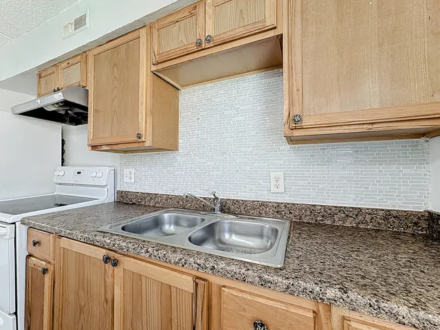 a kitchen with granite countertop a sink stove and cabinets