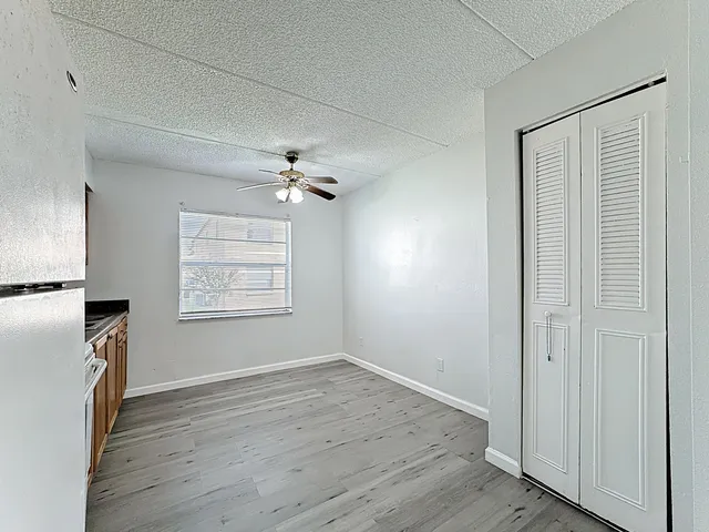 an empty room with wooden floor chandelier fan and windows