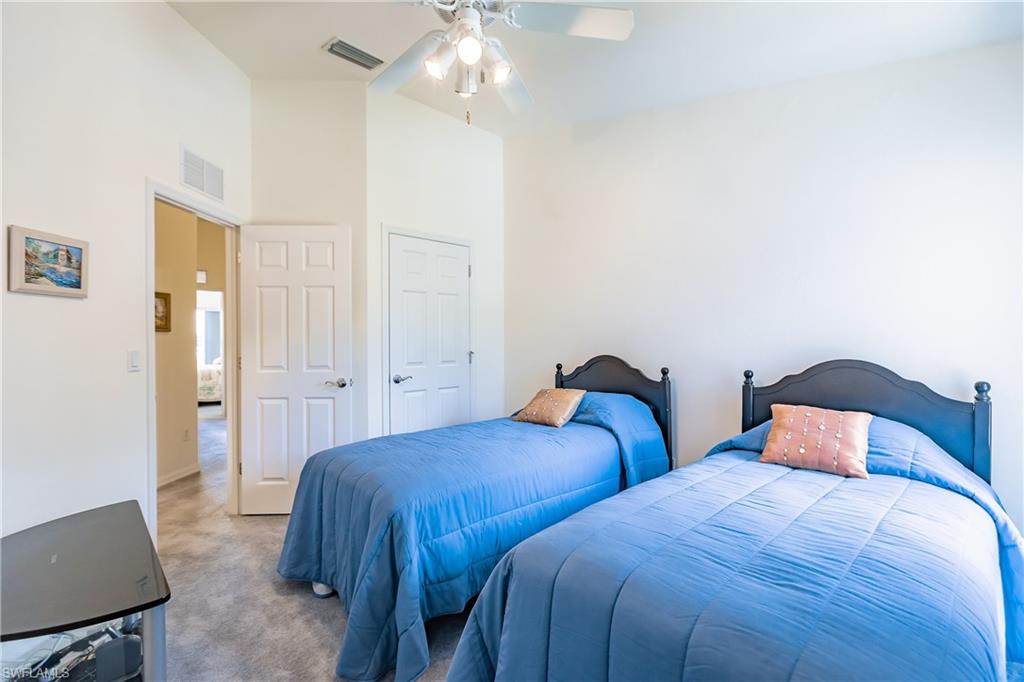15451 Marcello Circle, Unit 229 Naples, FL 34110 - Photo 22 of 30 a bedroom with two beds and a chandelier