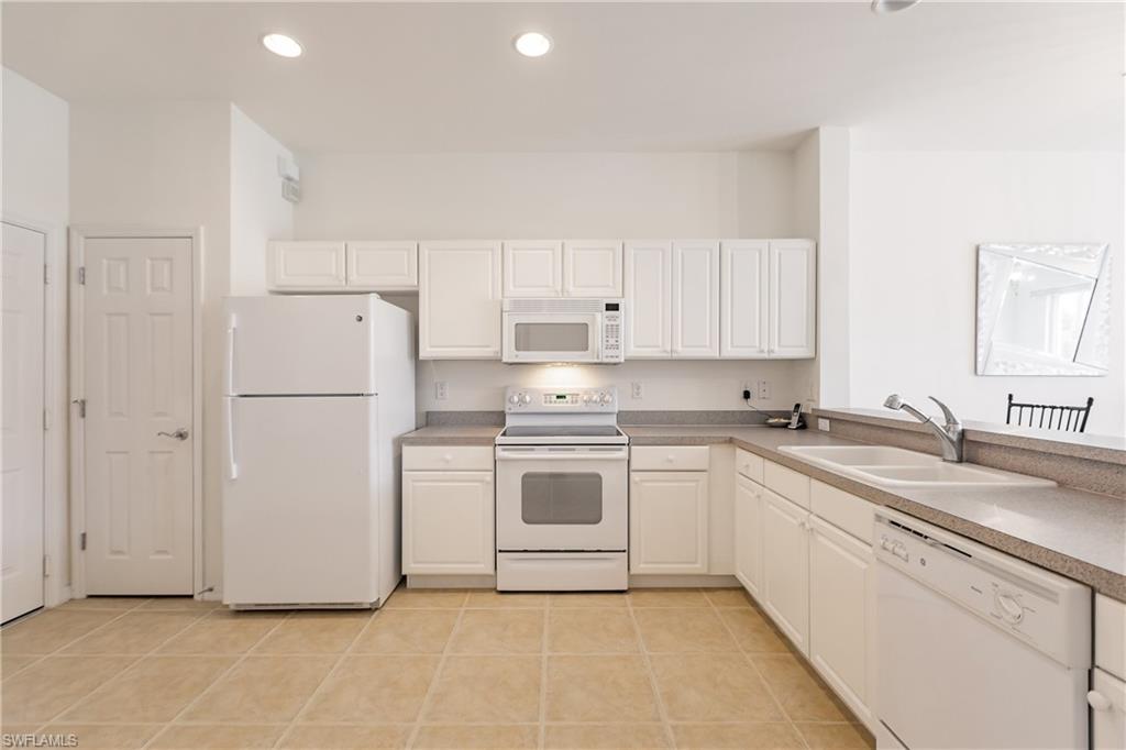 15451 Marcello Circle, Unit 229 Naples, FL 34110 - Photo 6 of 30 a kitchen with a white cabinets and white appliances