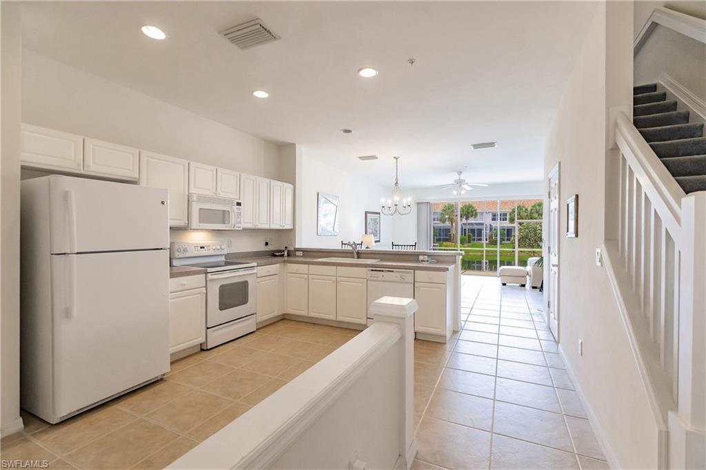 15451 Marcello Circle, Unit 229 Naples, FL 34110 - Photo 9 of 30 a kitchen with white cabinets and white appliances