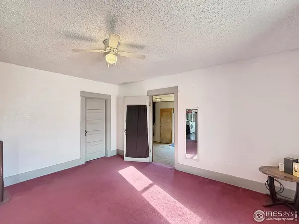 an empty room with closet and a chandelier fan