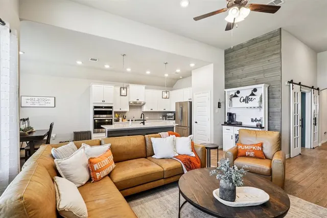 a living room with furniture kitchen view and a chandelier