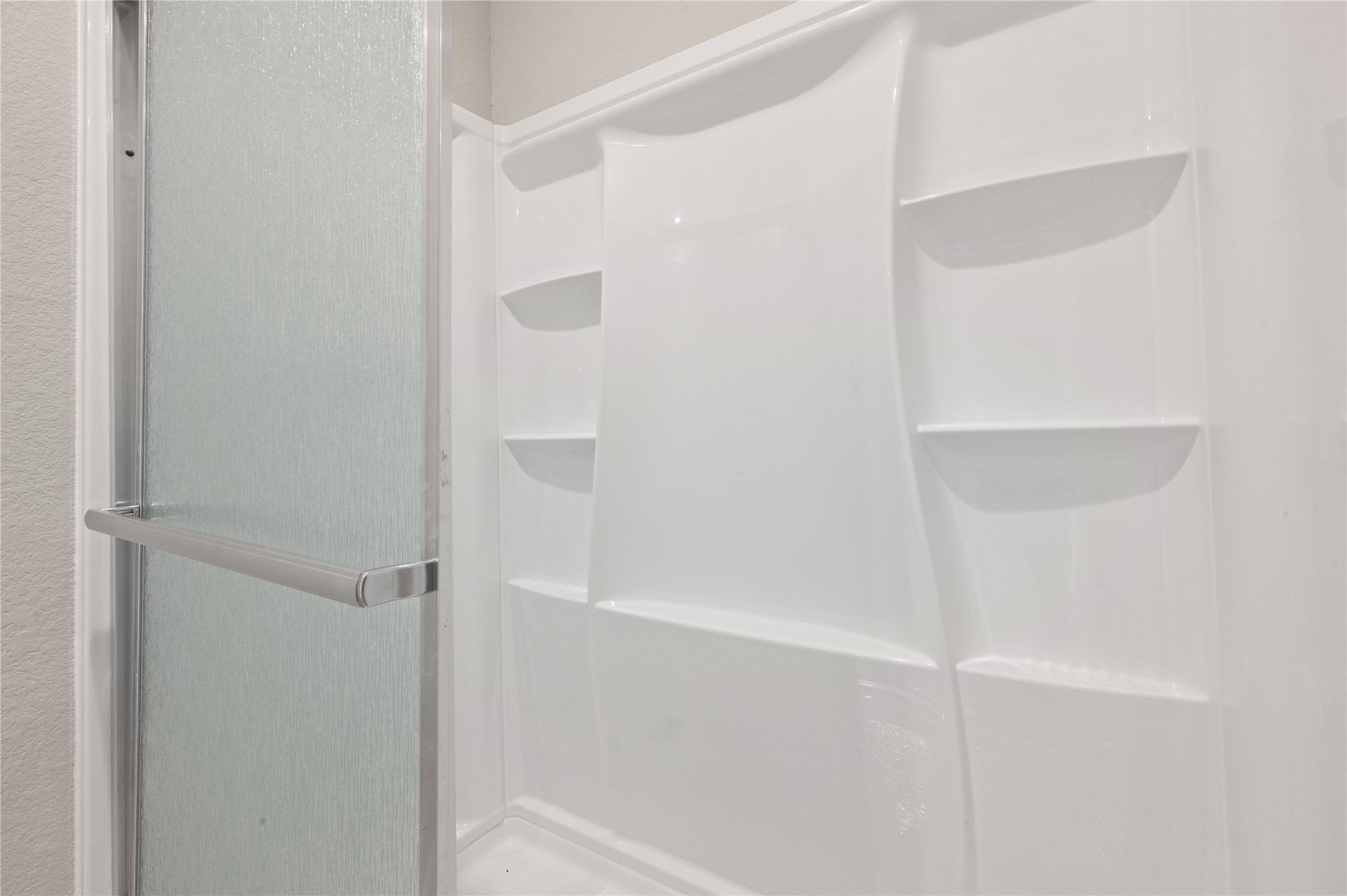 14010 Longstreet Road, Unit 2 Willis, TX 77318 - Photo 13 of 29 This photo shows a modern, white walk-in shower with built-in shelving and a sliding glass door, ideal for a clean and functional bathroom space.
