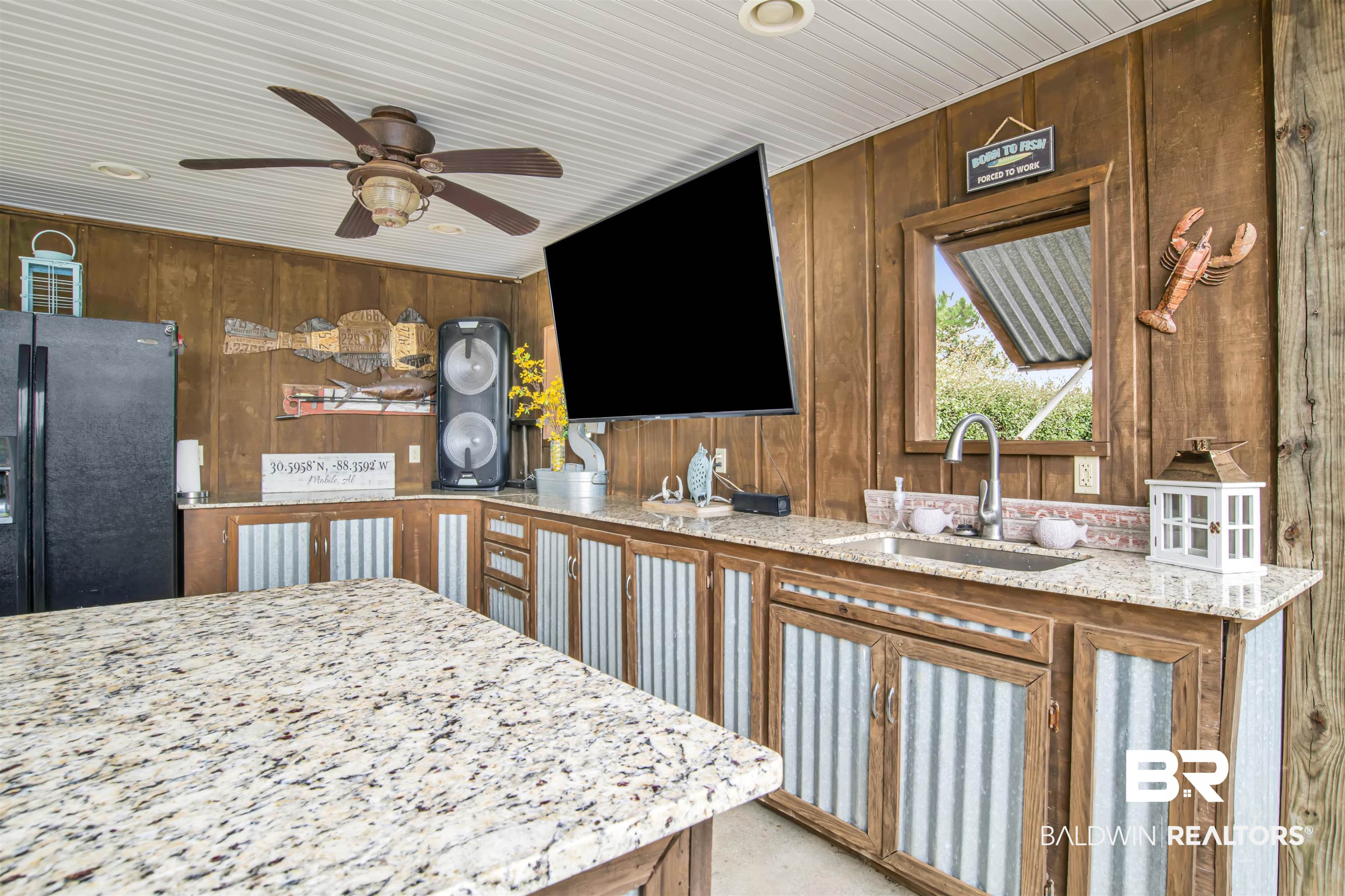 13385 Tom Gaston Road Mobile, AL 36695 - Photo 27 of 42 Kitchen featuring ceiling fan, wood walls, sink, light stone countertops, and black refrigerator