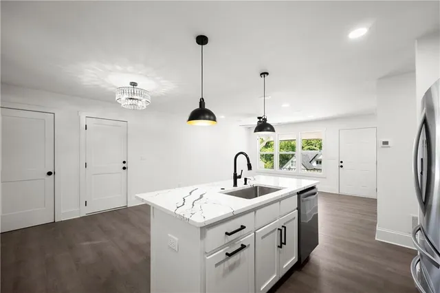 a kitchen with stainless steel appliances granite countertop a sink a refrigerator and a view of living room