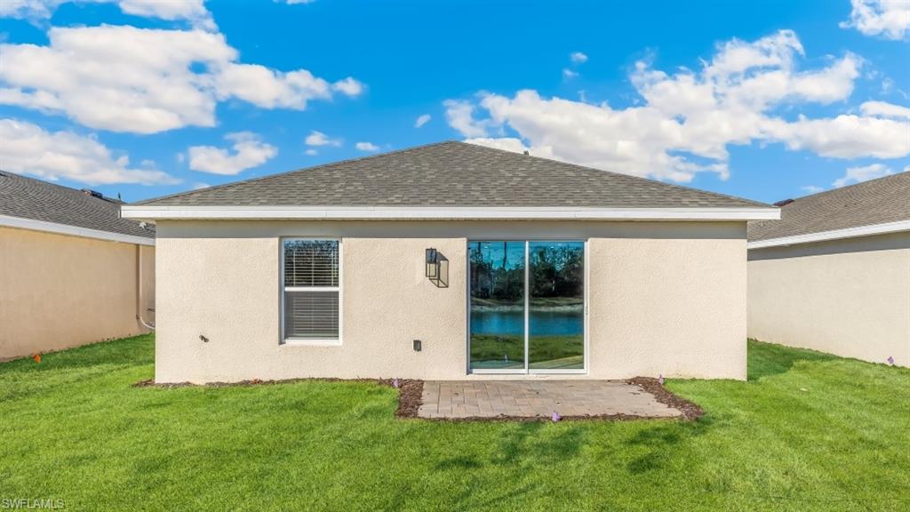 8052 Cedar Ky Way Lehigh Acres, FL 33971 - Photo 27 of 45 Model home. Back of house with a yard, stucco siding, a shingled roof, and a patio