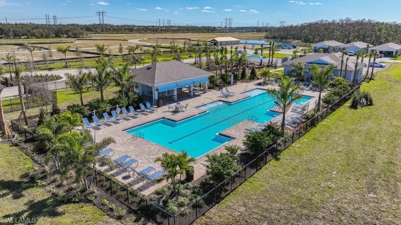 8052 Cedar Ky Way Lehigh Acres, FL 33971 - Photo 36 of 45 The property features an extensive outdoor swimming pool with a paved deck, surrounded by sun loungers and palm trees