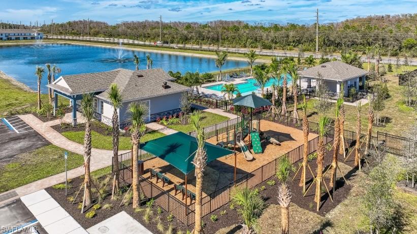 8052 Cedar Ky Way Lehigh Acres, FL 33971 - Photo 44 of 45 Community amenities include a playground with a shade structure, a pool, and a recreational building, all situated alongside a body of water