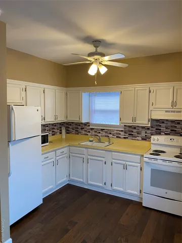 a kitchen with stainless steel appliances granite countertop a stove a sink and white cabinets