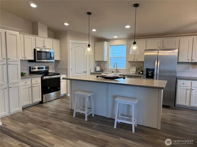 a kitchen with kitchen island granite countertop a sink a counter top space stainless steel appliances and cabinets