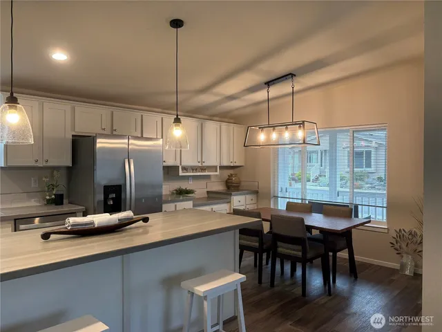 a kitchen with granite countertop a dining table chairs refrigerator and cabinets