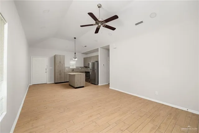 a view of a livingroom with a ceiling fan and kitchen space